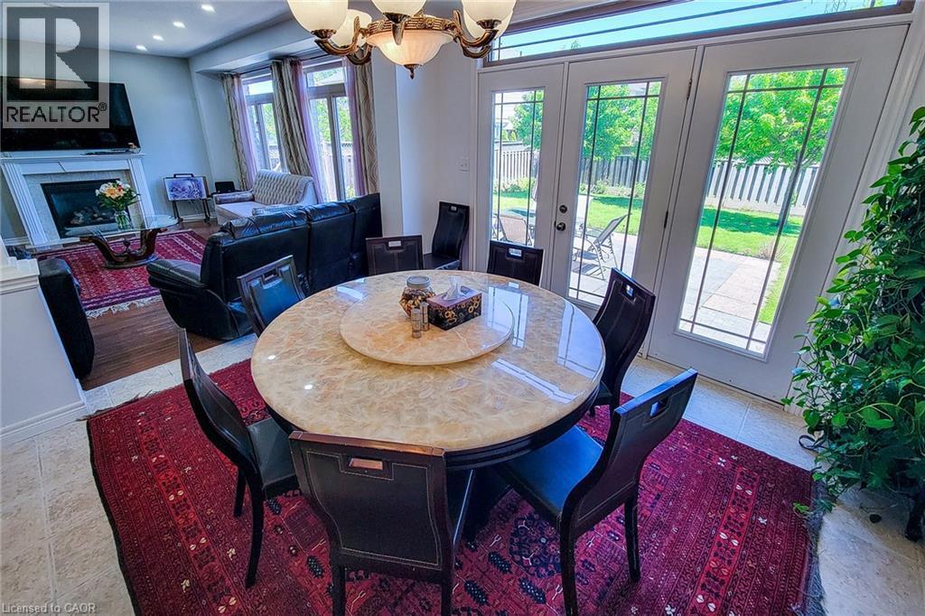 Dining area featuring a circular table with a light-toned, veined surface, illuminated by a multi-bulb chandelier - 197 Cloverleaf Drive, Ancaster, ON - Indoor Photo Showing Dining Room With Fireplace