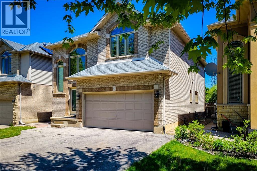 Brick and stone facade residence featuring an integrated two-car garage, arched windows, a covered front entryway, and a paved driveway - 197 Cloverleaf Drive, Ancaster, ON - Outdoor