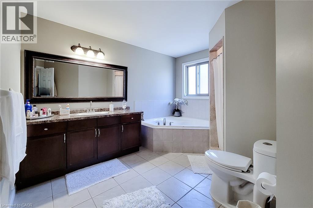 Spacious bathroom featuring a large vanity with double sinks, dark wood-finish cabinetry, and a stone-finish countertop - 197 Cloverleaf Drive, Ancaster, ON - Indoor Photo Showing Bathroom