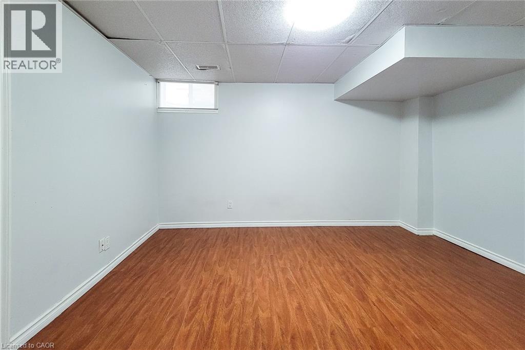 Spacious room featuring wood-finish flooring, white baseboards, and bright white walls - 197 Cloverleaf Drive, Ancaster, ON - Indoor Photo Showing Other Room