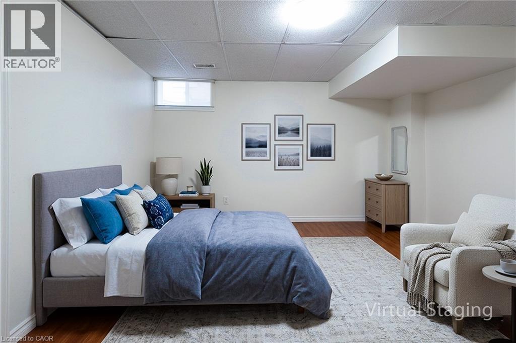 Hardwood-style flooring highlights this spacious room with a drop ceiling and integrated lighting - 197 Cloverleaf Drive, Ancaster, ON - Indoor Photo Showing Bedroom