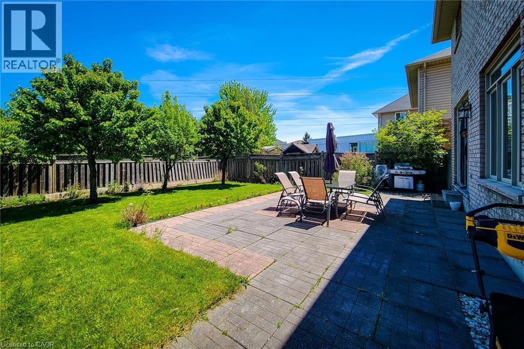 Expansive backyard featuring a green lawn, mature trees, a privacy fence, and a stone paver patio - 197 Cloverleaf Drive, Ancaster, ON - Outdoor