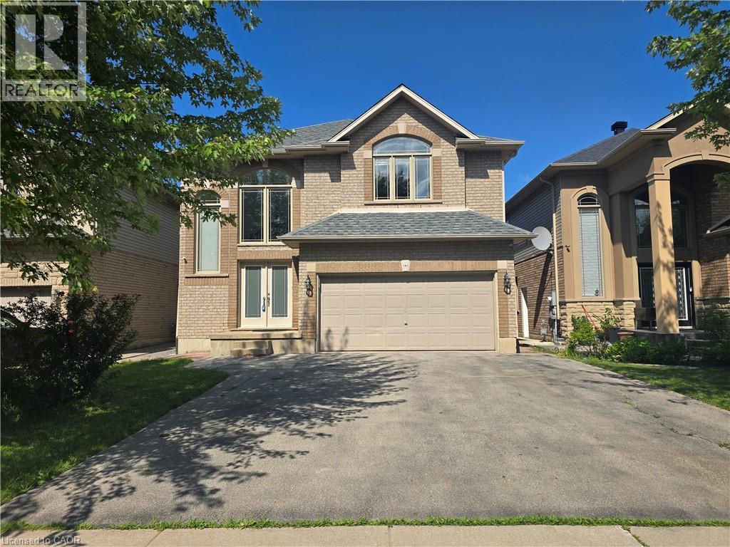 Brick exterior with a peaked roofline, front-facing two-car garage, multiple upper-level windows, and a double-door entryway - 197 Cloverleaf Drive, Ancaster, ON - Outdoor With Facade