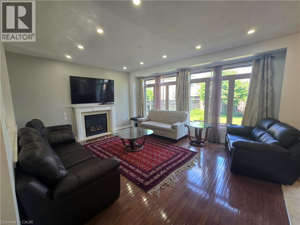 Living space featuring wood-finish flooring, a white mantel fireplace, and recessed ceiling lighting - 197 Cloverleaf Drive, Ancaster, ON - Indoor Photo Showing Living Room With Fireplace
