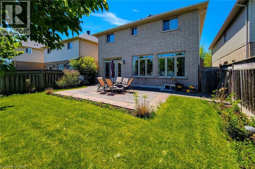 Expansive backyard featuring a large paved patio, ample green space, and a brick exterior with multiple windows - 197 Cloverleaf Drive, Ancaster, ON - Outdoor
