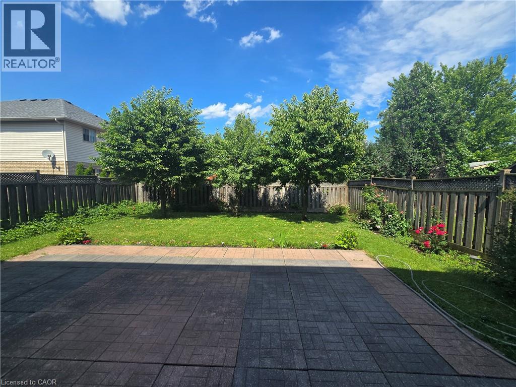 Expansive backyard featuring a large paved patio area, manicured lawn, and mature trees - 197 Cloverleaf Drive, Ancaster, ON - Outdoor With Exterior