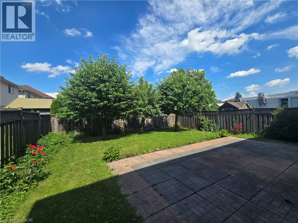 Expansive backyard featuring a paver patio, lush green lawn, mature trees, and perimeter fencing - 197 Cloverleaf Drive, Ancaster, ON - Outdoor With View