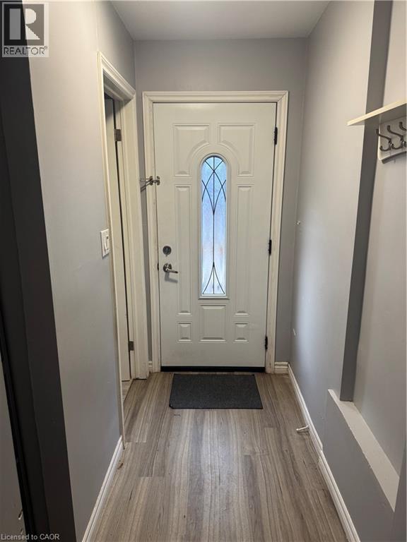Entryway featuring a panel door with decorative glass inserts, wood-finish flooring, and light gray wall paint - 61 E Waterloo Drive Unit# 61, Kitchener, ON - Indoor Photo Showing Other Room