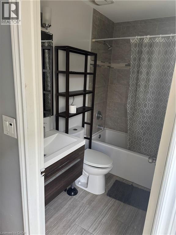 Bathroom featuring a contemporary floating vanity with integrated sink, a white bathtub with tile surround, and wood-finish flooring - 61 E Waterloo Drive Unit# 61, Kitchener, ON - Indoor Photo Showing Bathroom