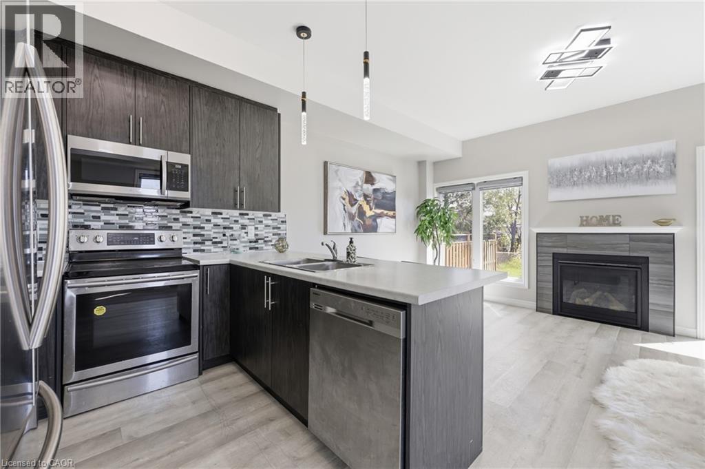 Modern kitchen featuring dark wood-finish cabinetry, stainless steel appliances, a tile backsplash, and light-toned countertops - 37 Delena Avenue S, Hamilton, ON - Indoor Photo Showing Kitchen With Double Sink With Upgraded Kitchen
