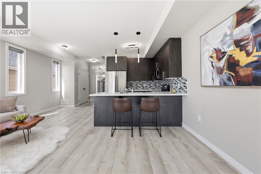 Open-concept living area featuring light wood-finish flooring, recessed lighting, and a kitchen island with seating - 37 Delena Avenue S, Hamilton, ON - Indoor Photo Showing Kitchen With Upgraded Kitchen