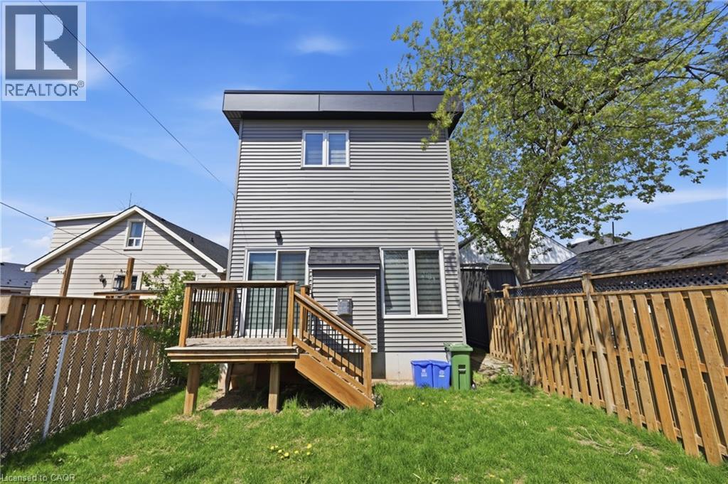 Rear exterior featuring gray horizontal siding, a flat roofline, and a raised wooden deck with stairs - 37 Delena Avenue S, Hamilton, ON - Outdoor