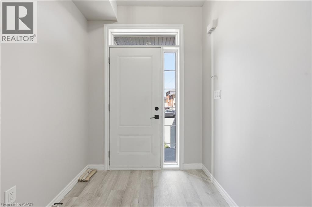 Entryway featuring a white paneled door with black hardware, a transom window, a side lite, light gray walls, and wood-finish flooring - 37 Delena Avenue S, Hamilton, ON - Indoor Photo Showing Other Room