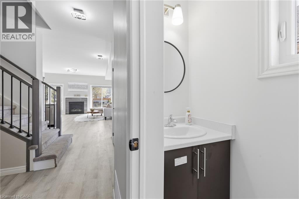 Powder room featuring a single vanity with a white countertop, under-mount sink, and a circular mirror - 37 Delena Avenue S, Hamilton, ON - Indoor Photo Showing Bathroom