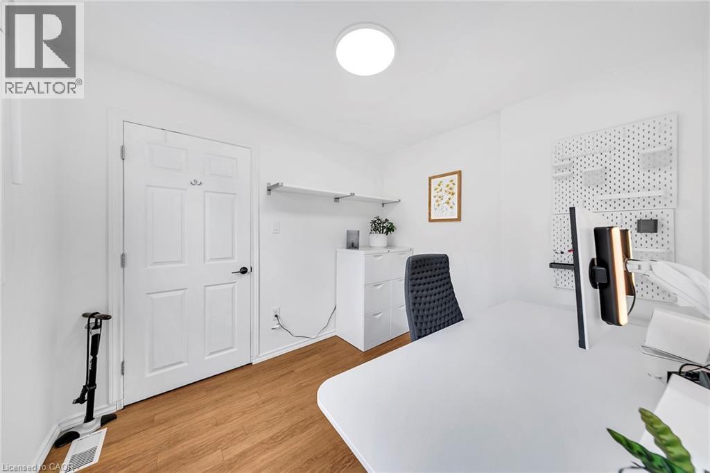 Bright room featuring wood-finish flooring and a white four-panel interior door with black hardware - 501 Ferguson Avenue N, Hamilton, ON - Indoor