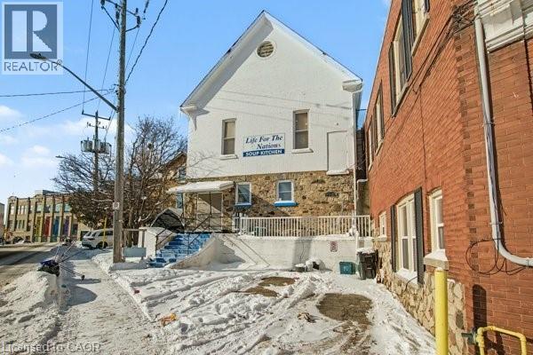 Stone and stucco facade building with a prominent peaked gable, multi-pane windows, blue exterior stairs, and a white railing - 37 Wellington Street, Cambridge, ON