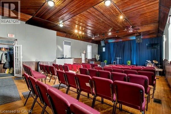 Spacious assembly room featuring a wood-panel ceiling, wood-finish flooring, recessed lighting, and white wainscoting - 37 Wellington Street, Cambridge, ON