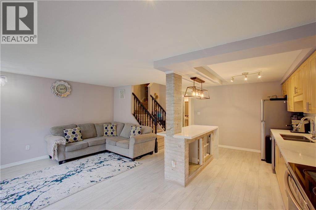 Open-concept living area featuring light wood-finish flooring, a kitchen with light wood cabinetry, and a peninsula with a light-toned countertop - 53 Prosperity Drive, Kitchener, ON - Indoor