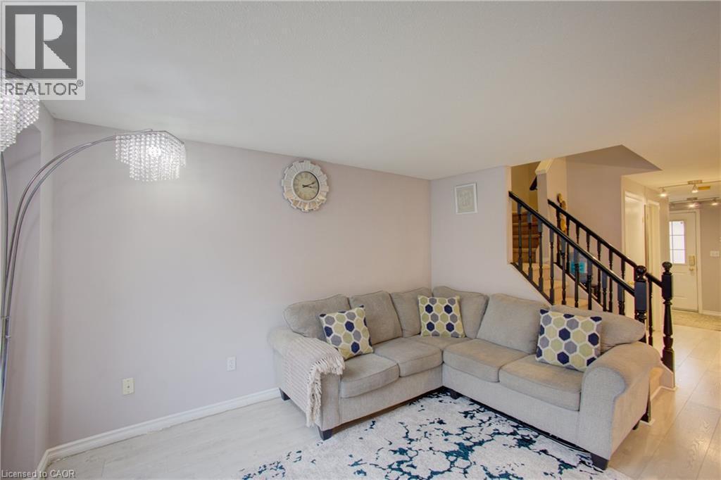 Open-concept living space featuring light wood-finish flooring and a staircase with dark wood newel posts and railings - 53 Prosperity Drive, Kitchener, ON - Indoor Photo Showing Living Room