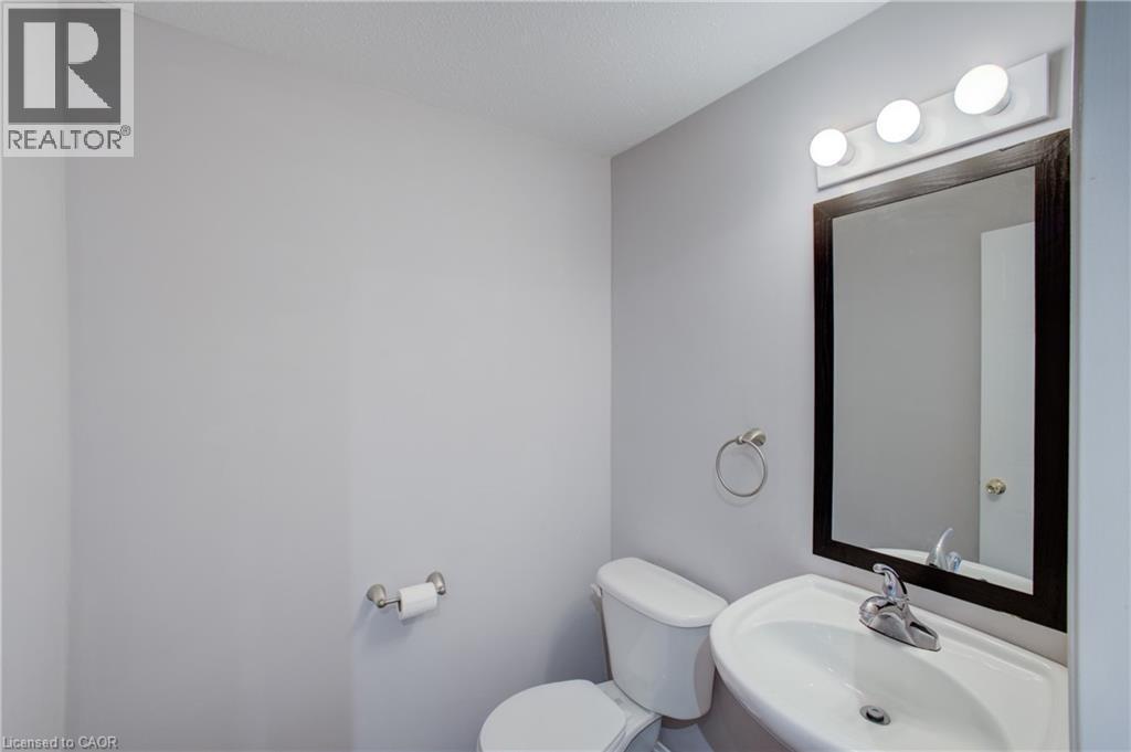 Powder room featuring a wall-mounted sink with chrome faucet, a dark-framed mirror, and a three-light vanity fixture - 53 Prosperity Drive, Kitchener, ON - Indoor Photo Showing Bathroom