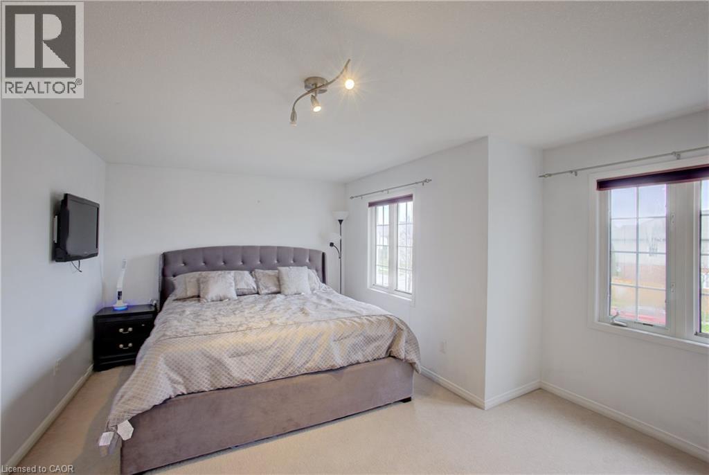 Light-filled interior space featuring track lighting, two distinct windows, and light-toned carpeting - 53 Prosperity Drive, Kitchener, ON - Indoor Photo Showing Bedroom