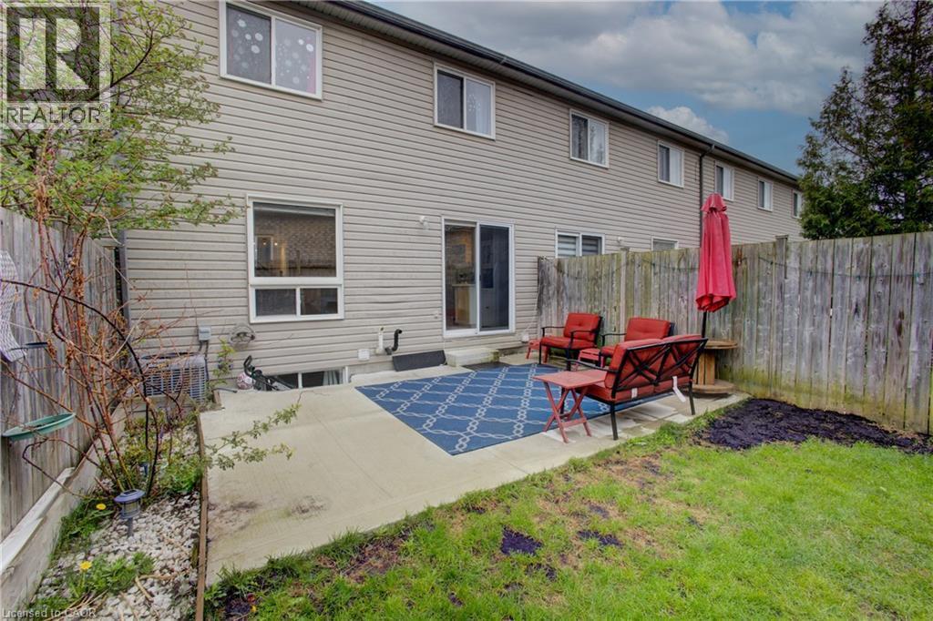 Rear exterior featuring light-colored siding, multiple windows, and a sliding glass door - 53 Prosperity Drive, Kitchener, ON - Outdoor With Exterior