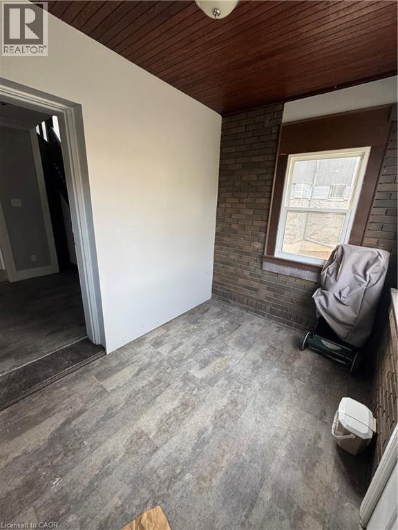 Room featuring wood-finish flooring, a wood-paneled ceiling, and a brick accent wall with a window - 61 Waterloo Drive, Kitchener, ON - Photo Showing Other Room