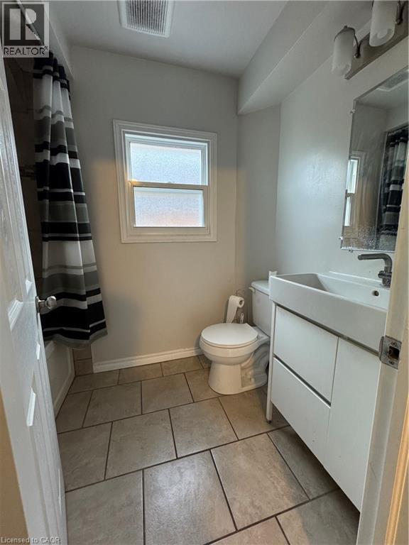 Bathroom featuring rectangular floor tiles and a white vanity with an integrated sink - 61 Waterloo Drive, Kitchener, ON - Indoor Photo Showing Bathroom