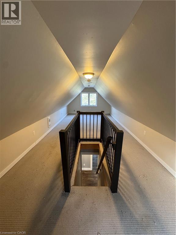 Attic space featuring sloped ceilings, light-toned carpeting, a central window, and a flush-mount ceiling light fixture - 61 Waterloo Drive, Kitchener, ON - Indoor Photo Showing Other Room