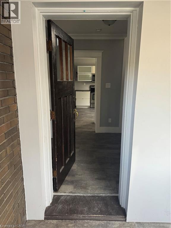 Dark wood entry door with glass paneling, brick exterior, and light-colored trim - 61 Waterloo Drive, Kitchener, ON - Photo Showing Other Room