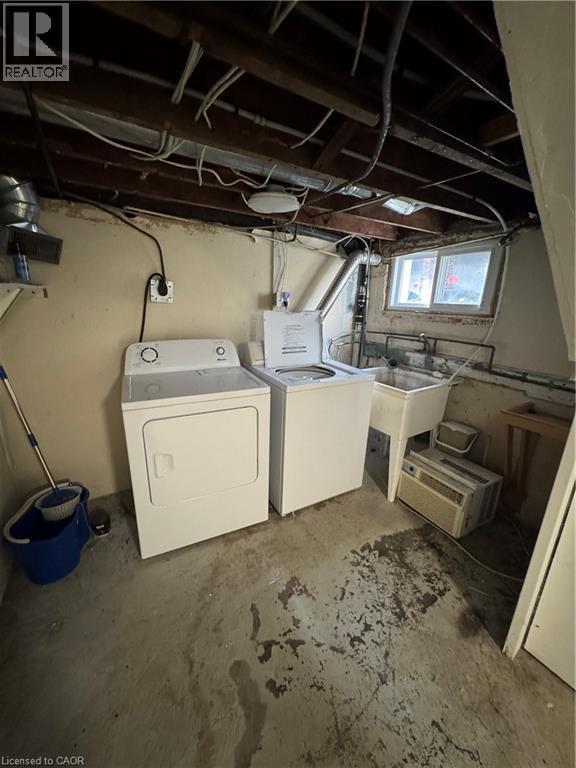 Utility area featuring exposed ceiling beams, concrete flooring, a basin sink, and a window providing natural light - 61 Waterloo Drive, Kitchener, ON - Indoor Photo Showing Laundry Room