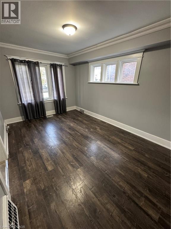 Spacious room featuring rich wood-finish flooring, crisp white baseboards, and elegant crown molding - 61 Waterloo Drive, Kitchener, ON - Indoor Photo Showing Other Room