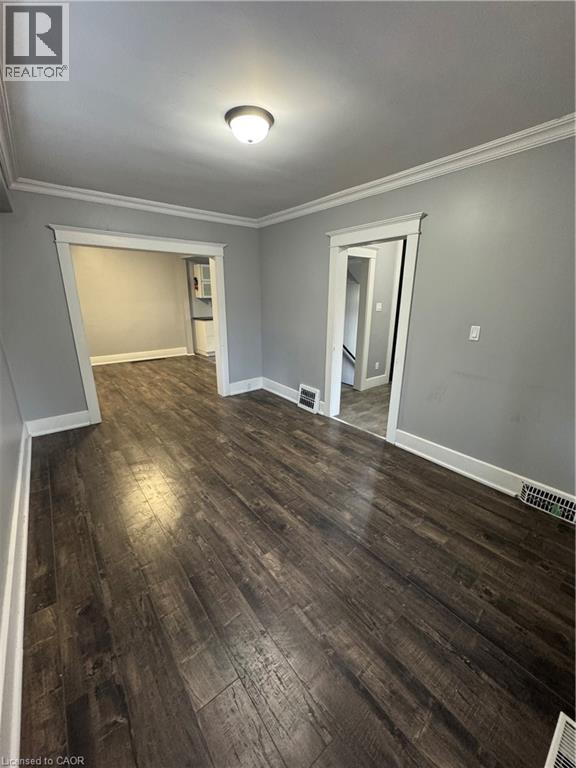 Expansive room featuring dark wood-finish flooring, light gray wall paint, and white crown molding - 61 Waterloo Drive, Kitchener, ON - Indoor Photo Showing Other Room