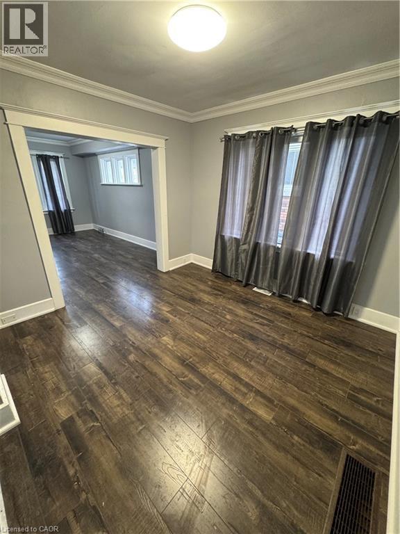 Spacious interior room featuring wood-finish flooring, light gray wall tones, and white crown molding - 61 Waterloo Drive, Kitchener, ON - Indoor Photo Showing Other Room