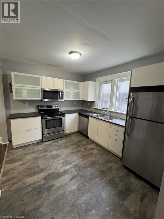 Kitchen featuring white cabinetry, dark countertops, stainless steel appliances, and wood-finish flooring - 61 Waterloo Drive, Kitchener, ON - Indoor Photo Showing Kitchen With Double Sink
