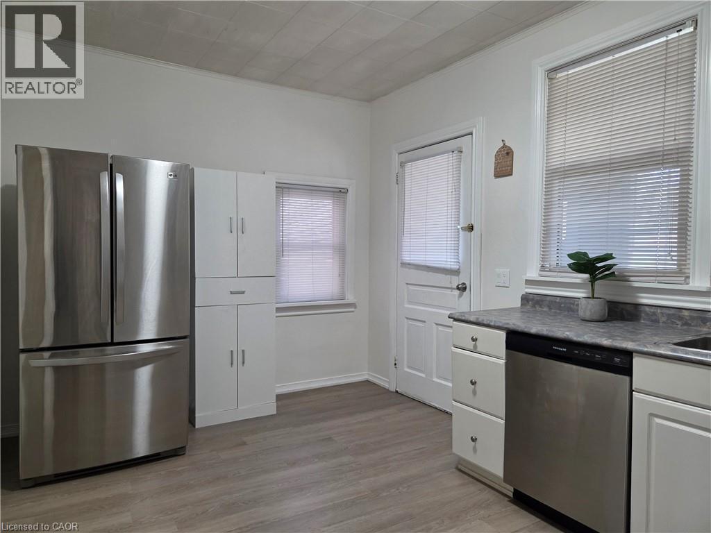 Kitchen featuring stainless steel appliances, wood-finish flooring, white cabinetry, and abundant natural light from multiple windows - 125 Cavell Avenue, Hamilton, ON - Indoor Photo Showing Kitchen