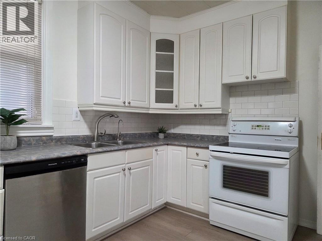 Kitchen featuring white shaker-style cabinetry, a stainless steel dishwasher, an electric range, and a subway tile backsplash - 125 Cavell Avenue, Hamilton, ON - Indoor Photo Showing Kitchen With Double Sink