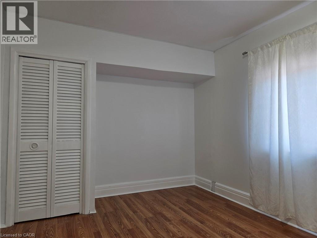 Room featuring wood-finish flooring, white baseboards, and a louvered bi-fold closet door - 125 Cavell Avenue, Hamilton, ON - Indoor Photo Showing Other Room
