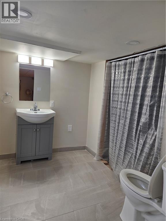 Bathroom featuring a gray vanity with an integrated sink, a rectangular wall-mounted mirror, and a three-light fixture above - 125 Cavell Avenue, Hamilton, ON - Indoor Photo Showing Bathroom