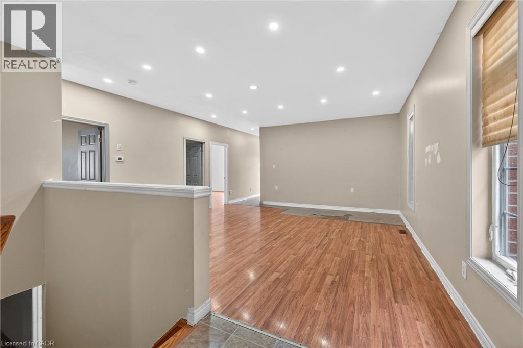 Open-concept interior featuring wood-finish flooring, recessed ceiling lighting, neutral wall tones, and white trim molding - 704 Stone Church Road E, Hamilton, ON - Indoor Photo Showing Other Room