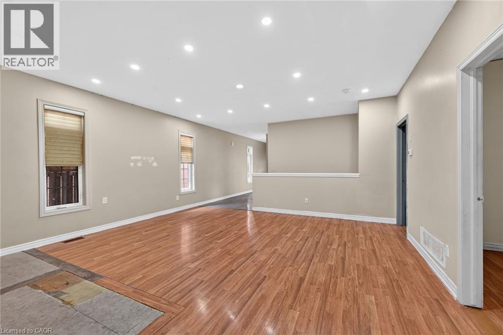 Spacious interior featuring wood-finish flooring, recessed ceiling lighting, neutral wall tones, and white trim - 704 Stone Church Road E, Hamilton, ON - Indoor Photo Showing Other Room