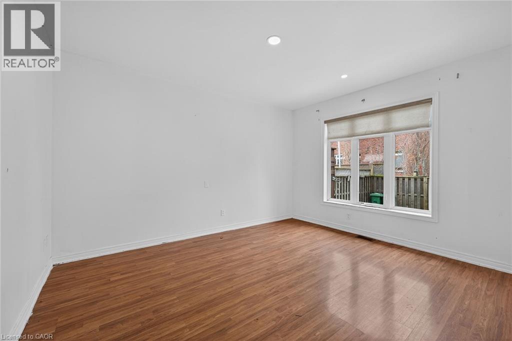 Room featuring wood-finish flooring, white baseboards, recessed lighting, and a large window with a roller shade - 704 Stone Church Road E, Hamilton, ON - Indoor Photo Showing Other Room