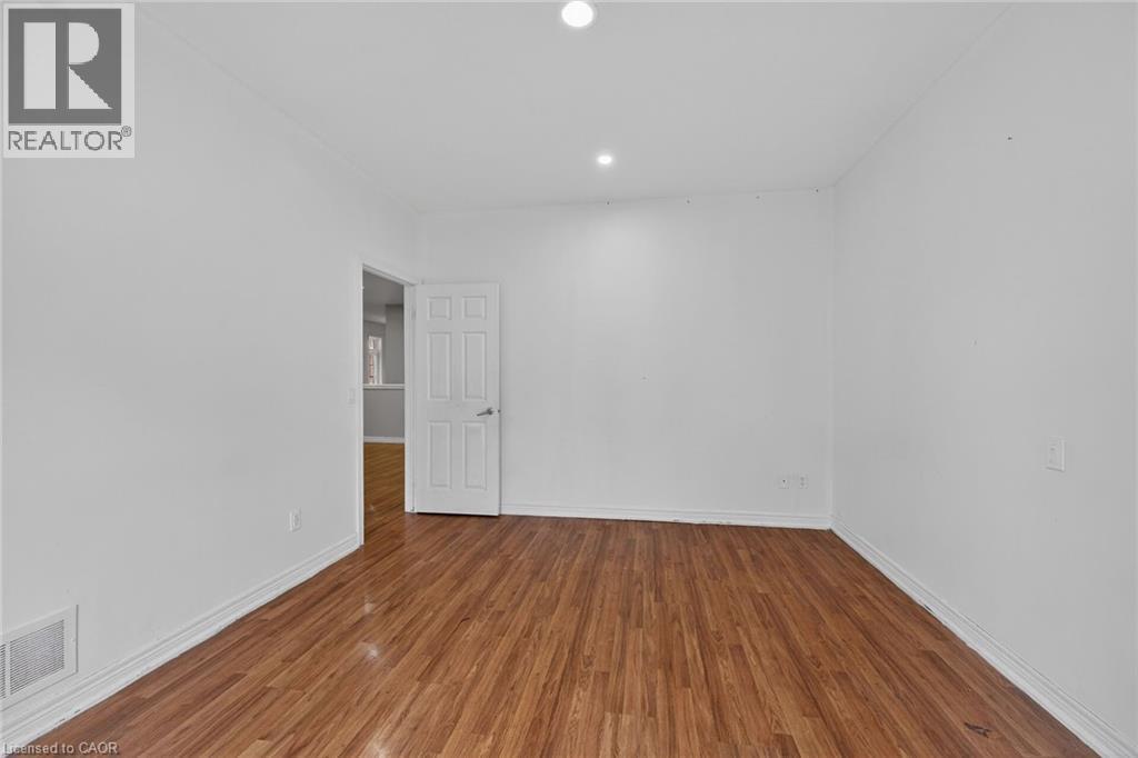 Interior room featuring wood-finish flooring, white walls, recessed ceiling lighting, and white baseboards - 704 Stone Church Road E, Hamilton, ON - Indoor Photo Showing Other Room