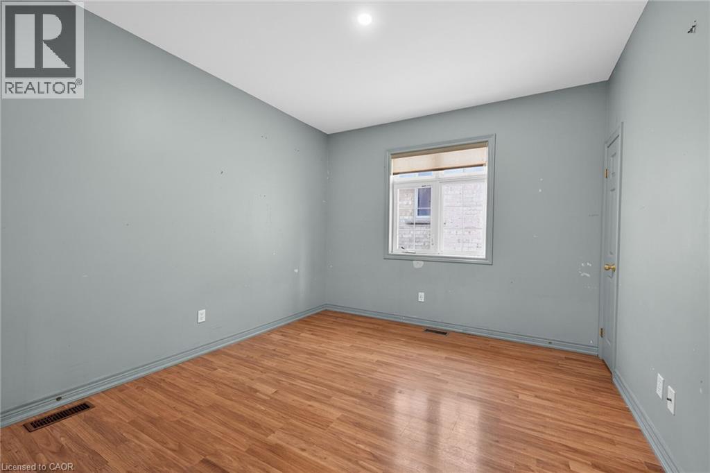 Kitchstone-finish countertops, stainless steel refrigerator, white electric range, and wood-finish flooring - 704 Stone Church Road E, Hamilton, ON - Indoor Photo Showing Other Room