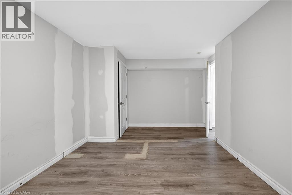 Room featuring wood-finish flooring, light gray wall paint, and a double-door closet with paneling - 704 Stone Church Road E, Hamilton, ON - Indoor Photo Showing Other Room