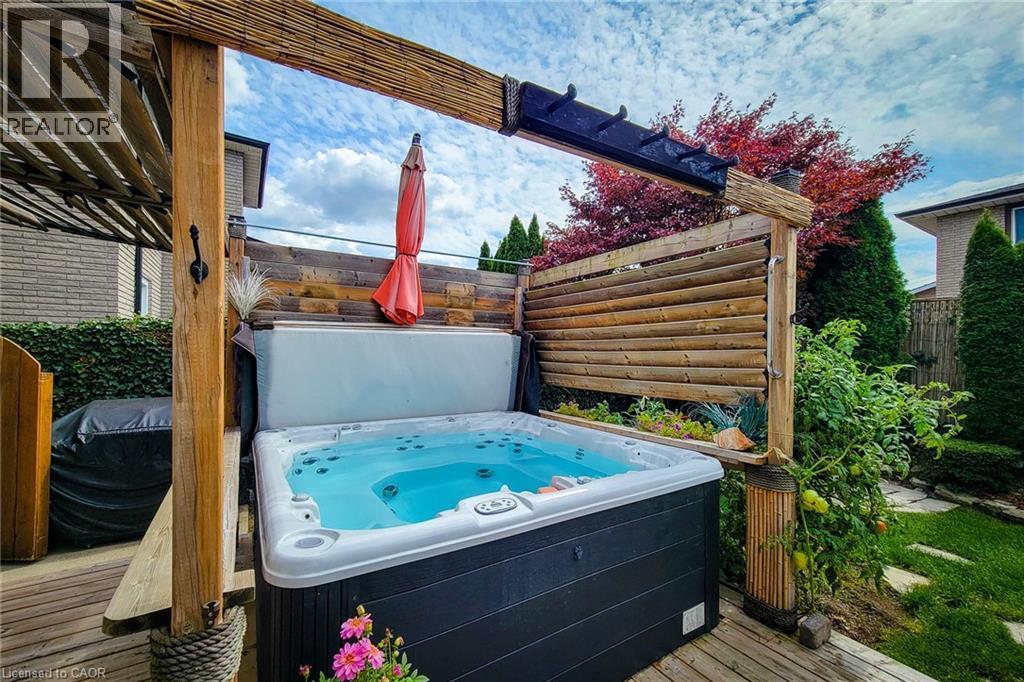 Outdoor spa area featuring a built-in hot tub, wood decking, and a slatted privacy fence - 146 Locheed Drive, Hamilton, ON - Outdoor With Deck Patio Veranda With Exterior
