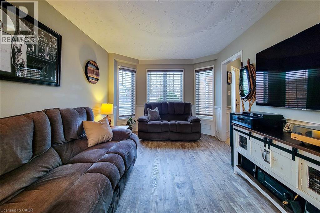 Living area featuring wood-finish flooring, a bay window with blinds, and neutral wall tones - 146 Locheed Drive, Hamilton, ON - Indoor Photo Showing Living Room