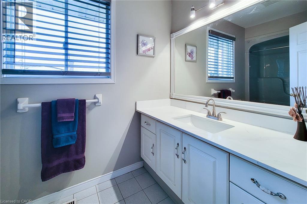 Bathroom featuring a white vanity with an integrated sink, brushed nickel faucet, and a large framed mirror - 146 Locheed Drive, Hamilton, ON - Indoor Photo Showing Bathroom