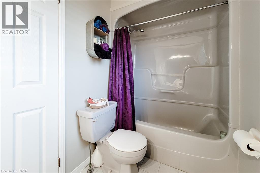 White paneled door opening to a bathroom featuring a white toilet, white tub-shower combination, and light gray walls - 146 Locheed Drive, Hamilton, ON - Indoor Photo Showing Bathroom