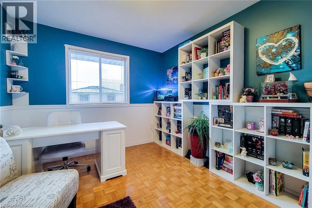 Versatile room featuring a large window, parquet wood-finish flooring, and extensive built-in shelving units - 146 Locheed Drive, Hamilton, ON - Indoor Photo Showing Other Room